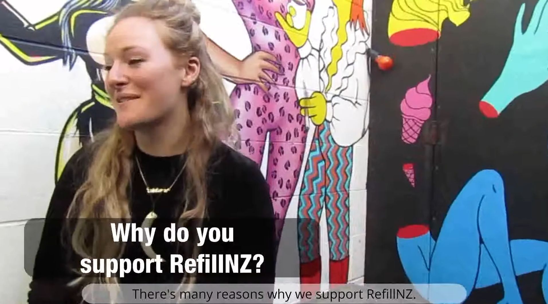 Still from The Refillution. A cafe worker answers the on-screen question “Why do you support RefillNZ?” in front of a brightly coloured street mural.